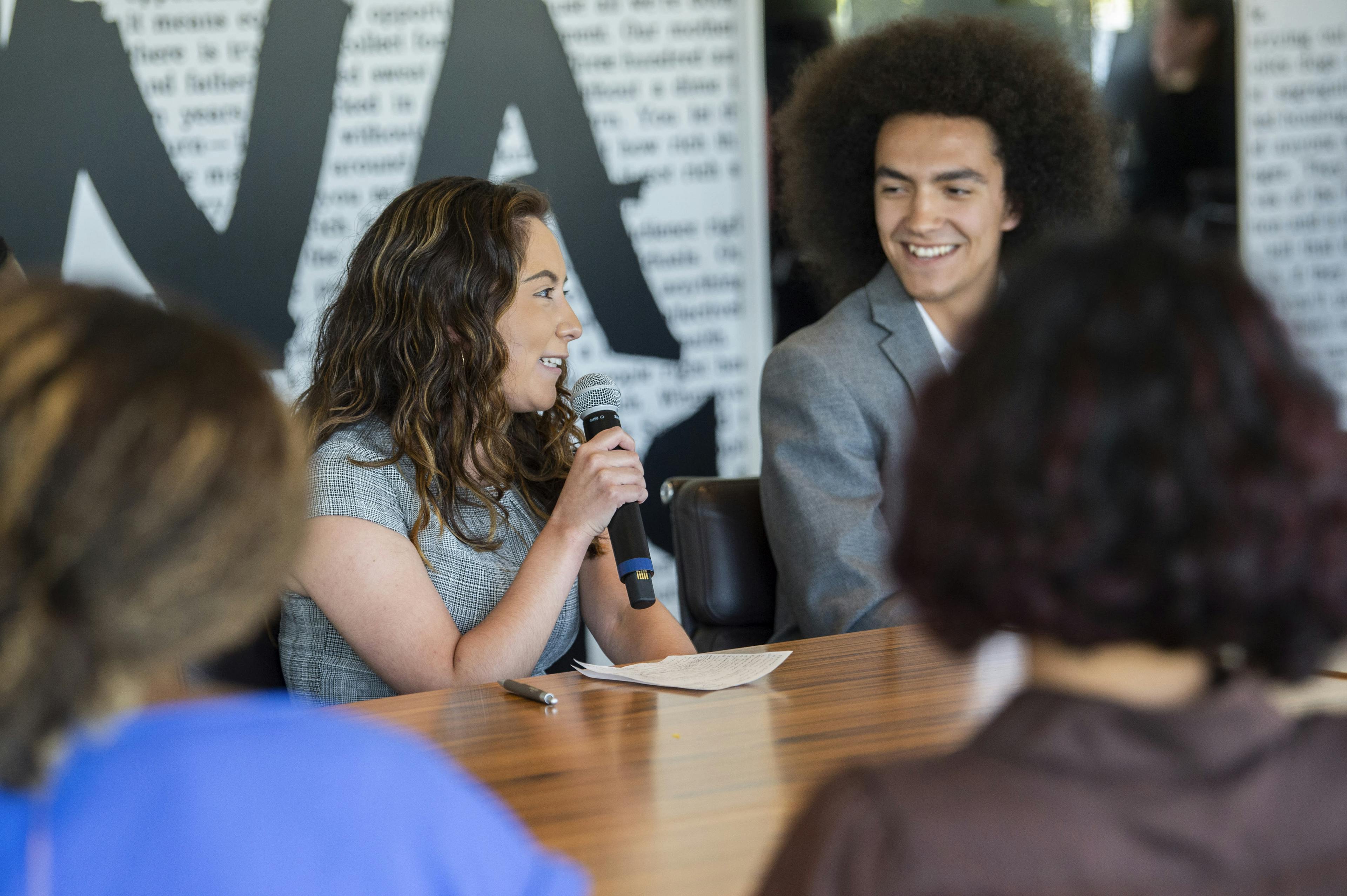Two interns smiling and speaking at a table