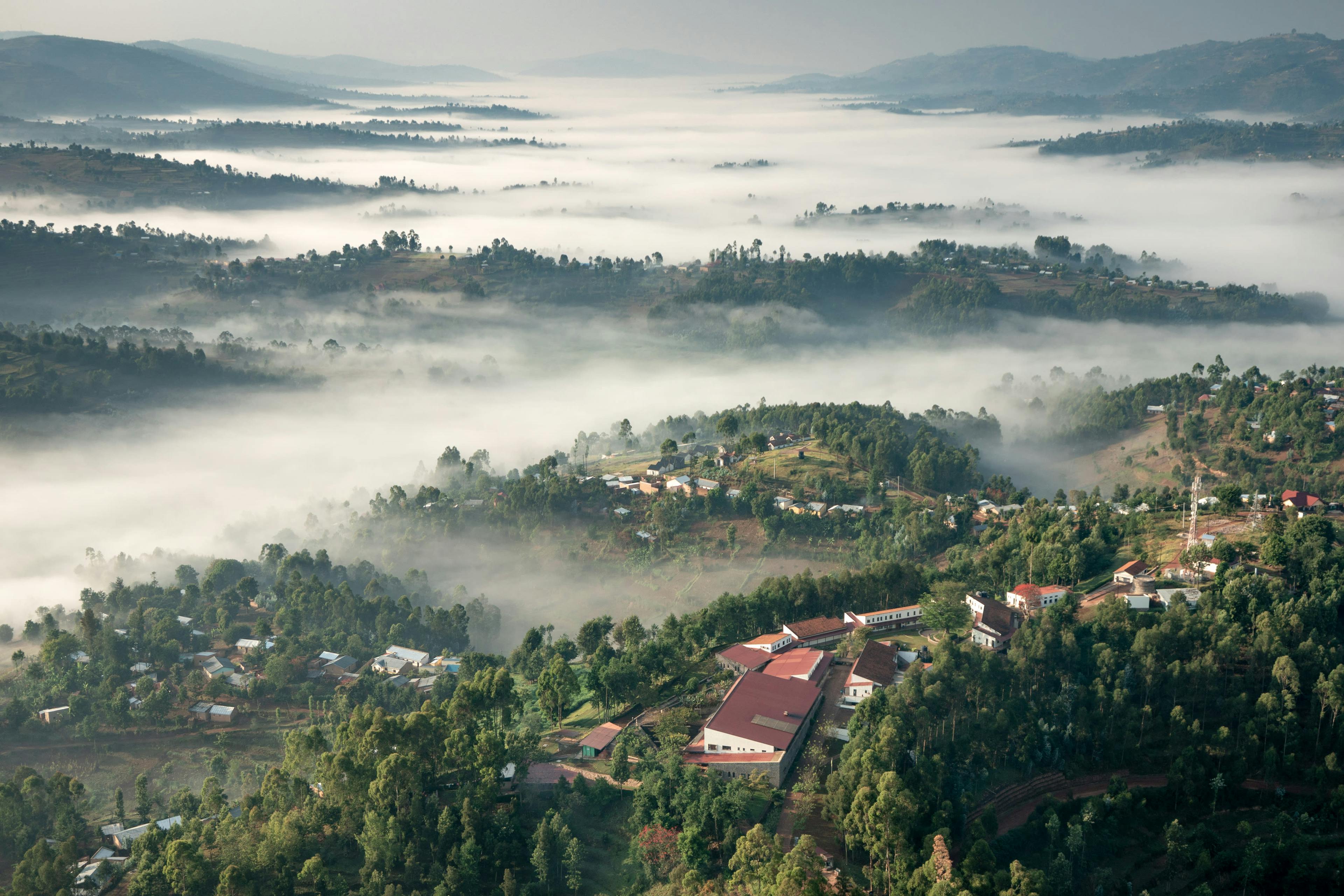A view from the sky down overlooking a lush valley with a marine layer and buildings.