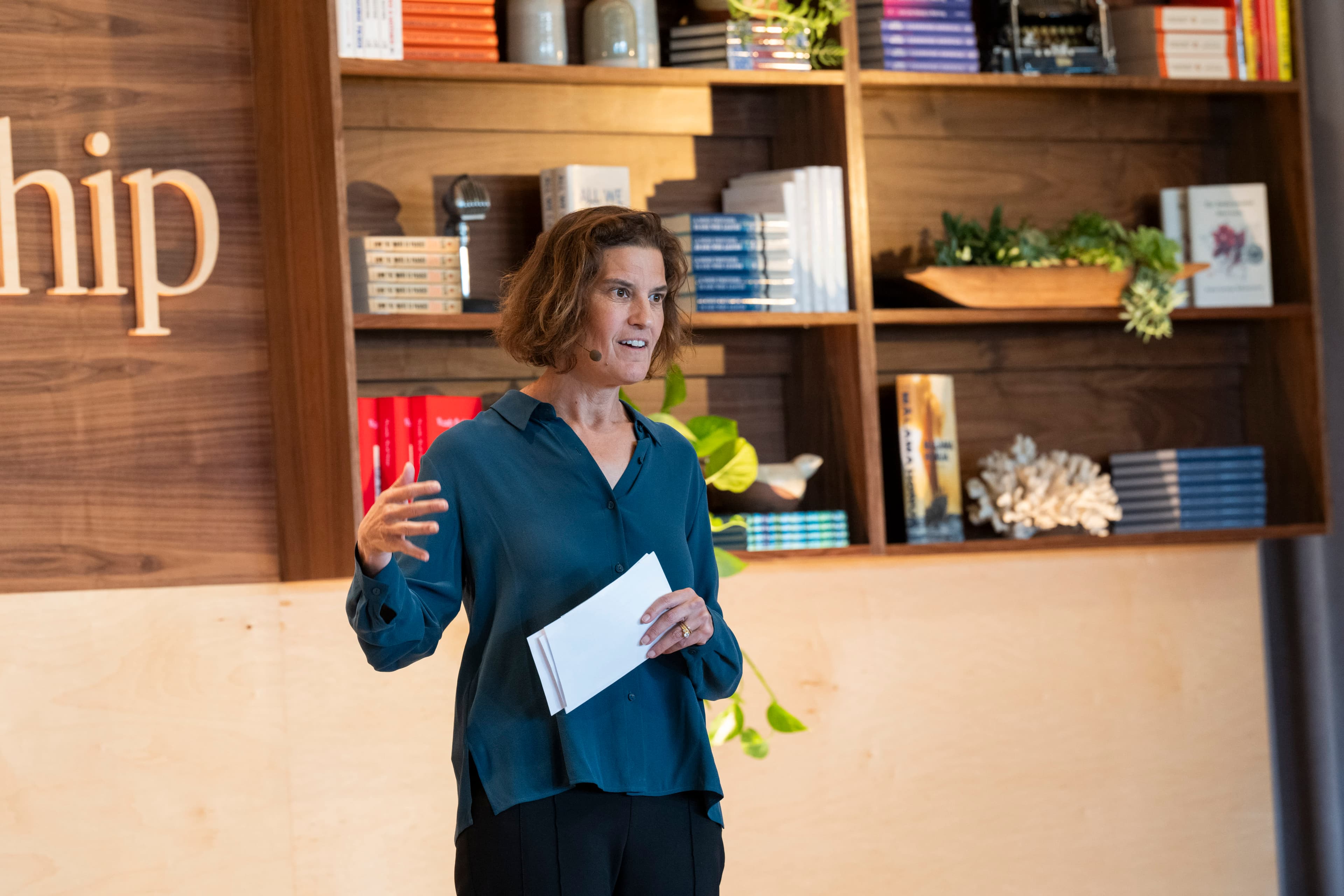 Joanna Strober speaking in front of a shelf