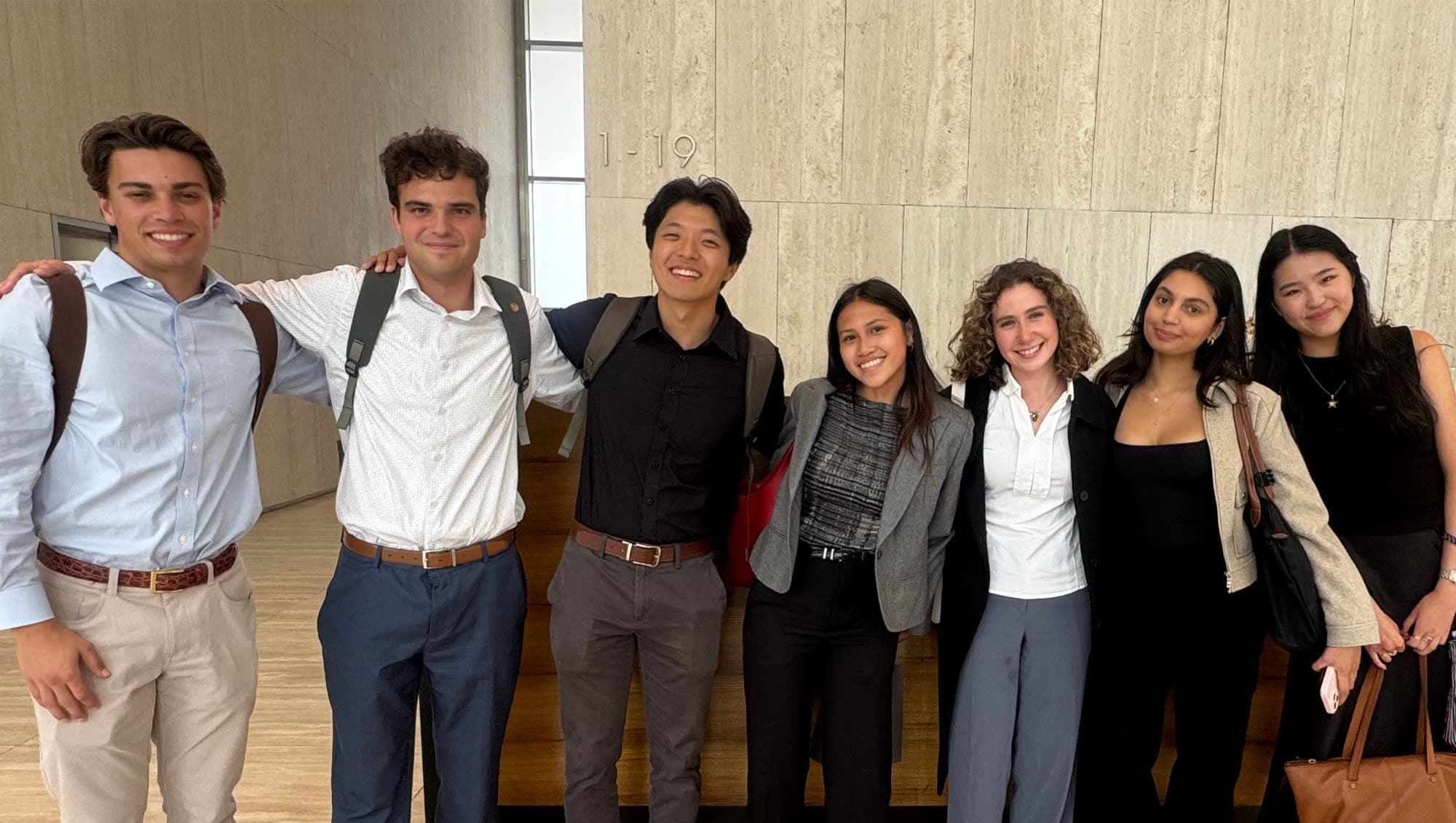 A group of students standing indoors in front of a couch